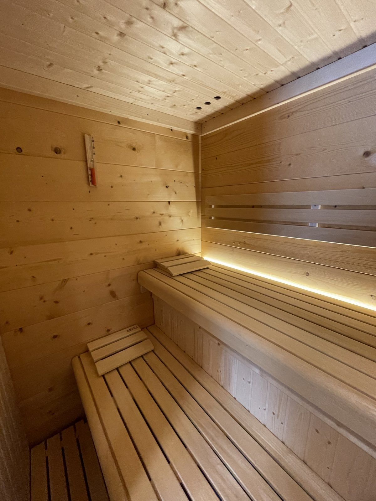 Notranjost finske savne z dvonivojskimi lesenimi klopmi in LED osvetlitvijo – Savne Cafuta